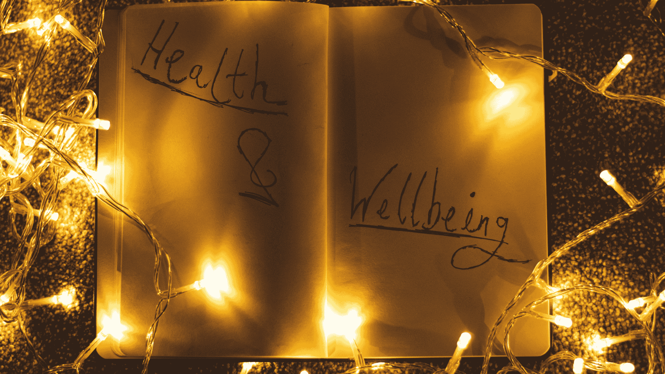 An open journal with 'Health & Wellbeing' written across its pages, glowing among warm string lights symbolizing the healing power of guided journal prompts for mental wellness