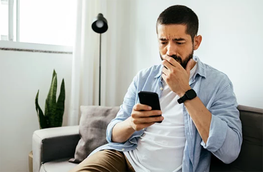 Adult man with a concerned face and looking at his phone texting 741741 for free mental health support.